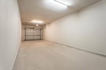 A long, narrow, empty room with a white ceiling and walls, and a metal gate in the middle.
